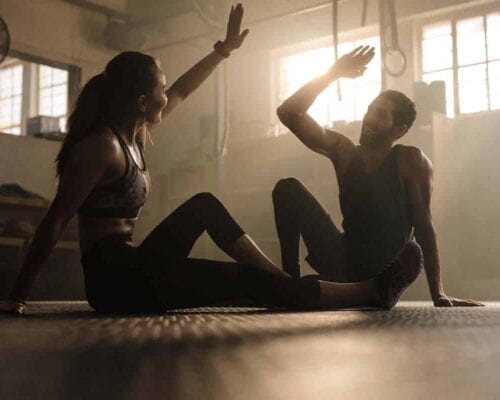 A couple practising fitness and wellness through yoga in a gym.