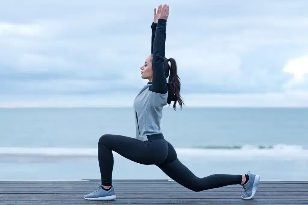 A woman doing squats in front of the ocean to promote wellness and fitness.