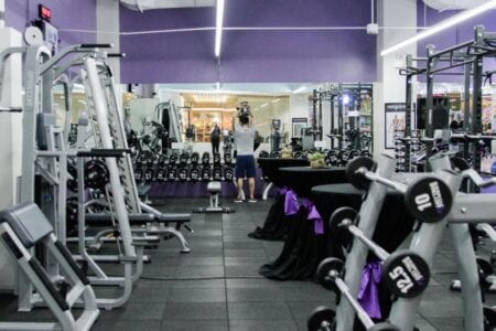 Un gimnasio en traspaso con una gran cantidad de equipos y paredes moradas.