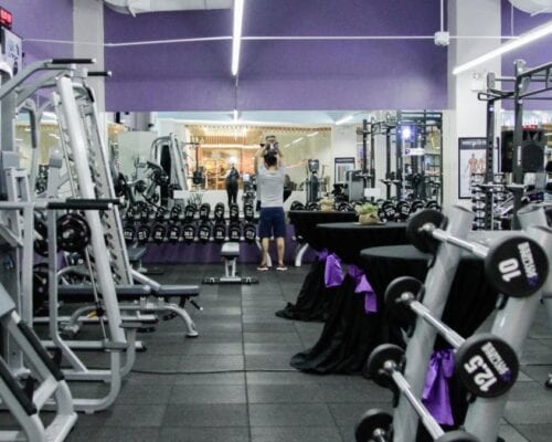A gymnasium for lease with a large amount of equipment and purple walls.