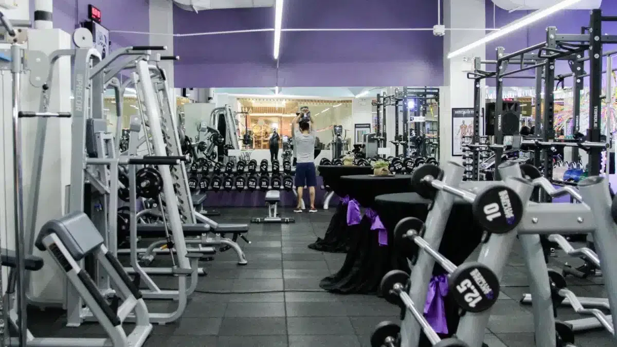 A gymnasium for lease with a large amount of equipment and purple walls.
